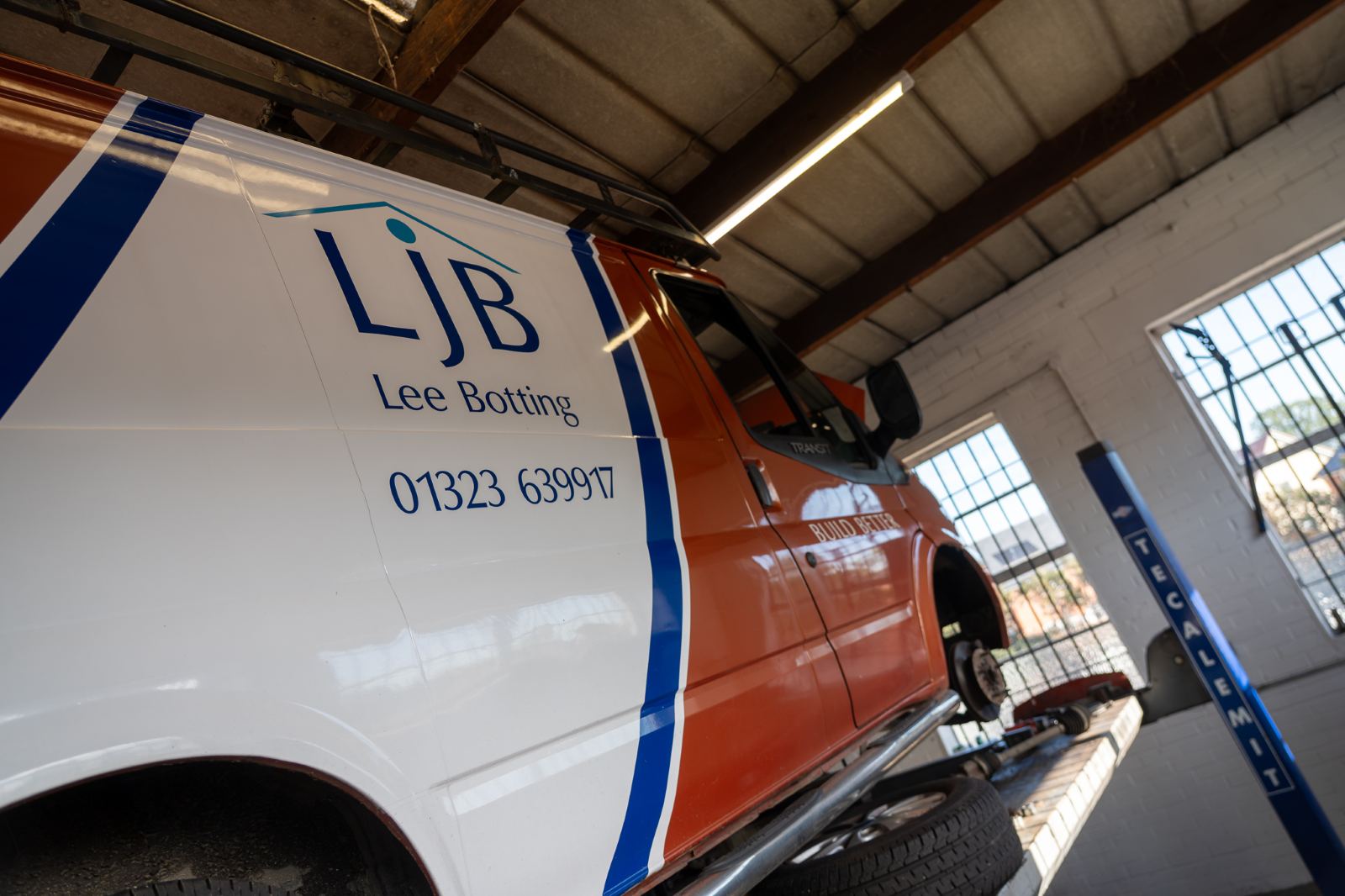 The LJB Lee Botting logo on the side of a van raised on the workshop lift